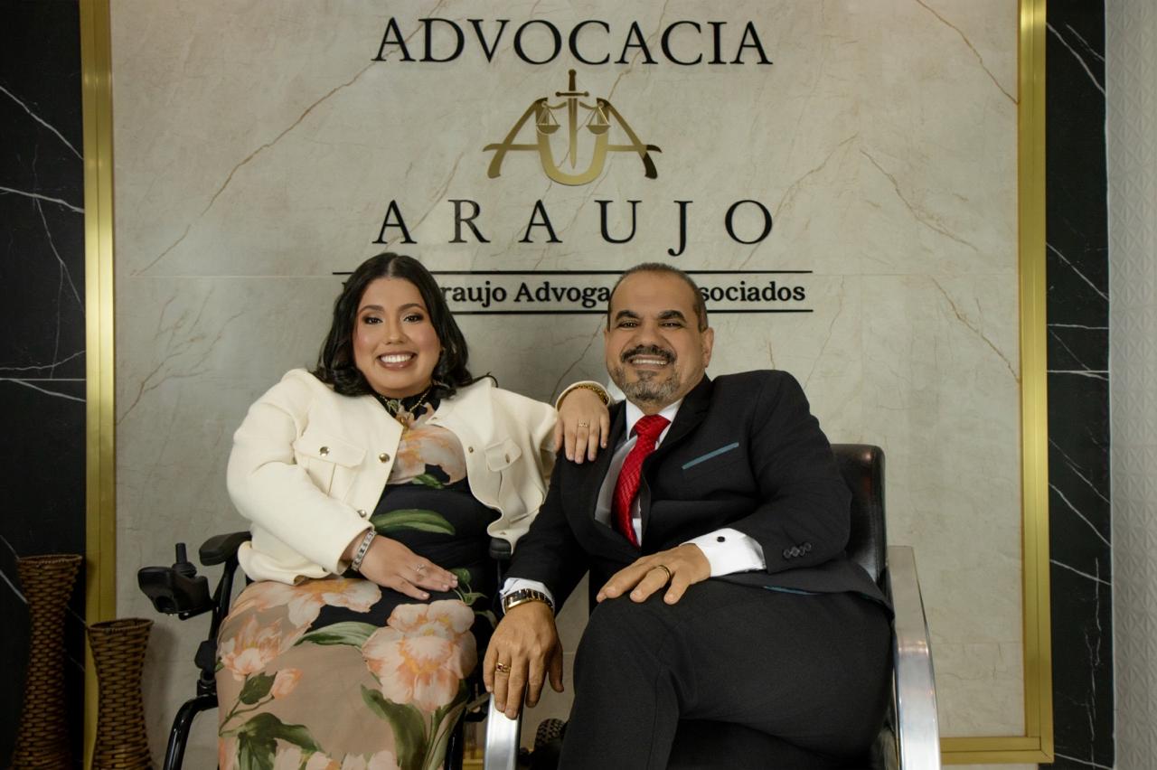 Fábio Araújo e Micaela Coutinho Araújo sentados diante da marca do escritório